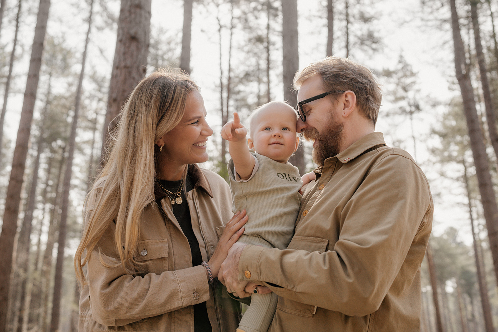 A young family walking through Sherwood Pines in Nottingham, holding hands and smiling during a relaxed springtime photoshoot.