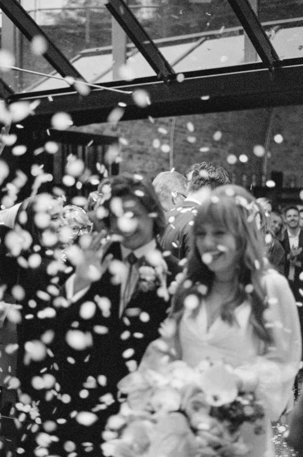 black and white photo of couple showered in confetti at 100 barrington road
