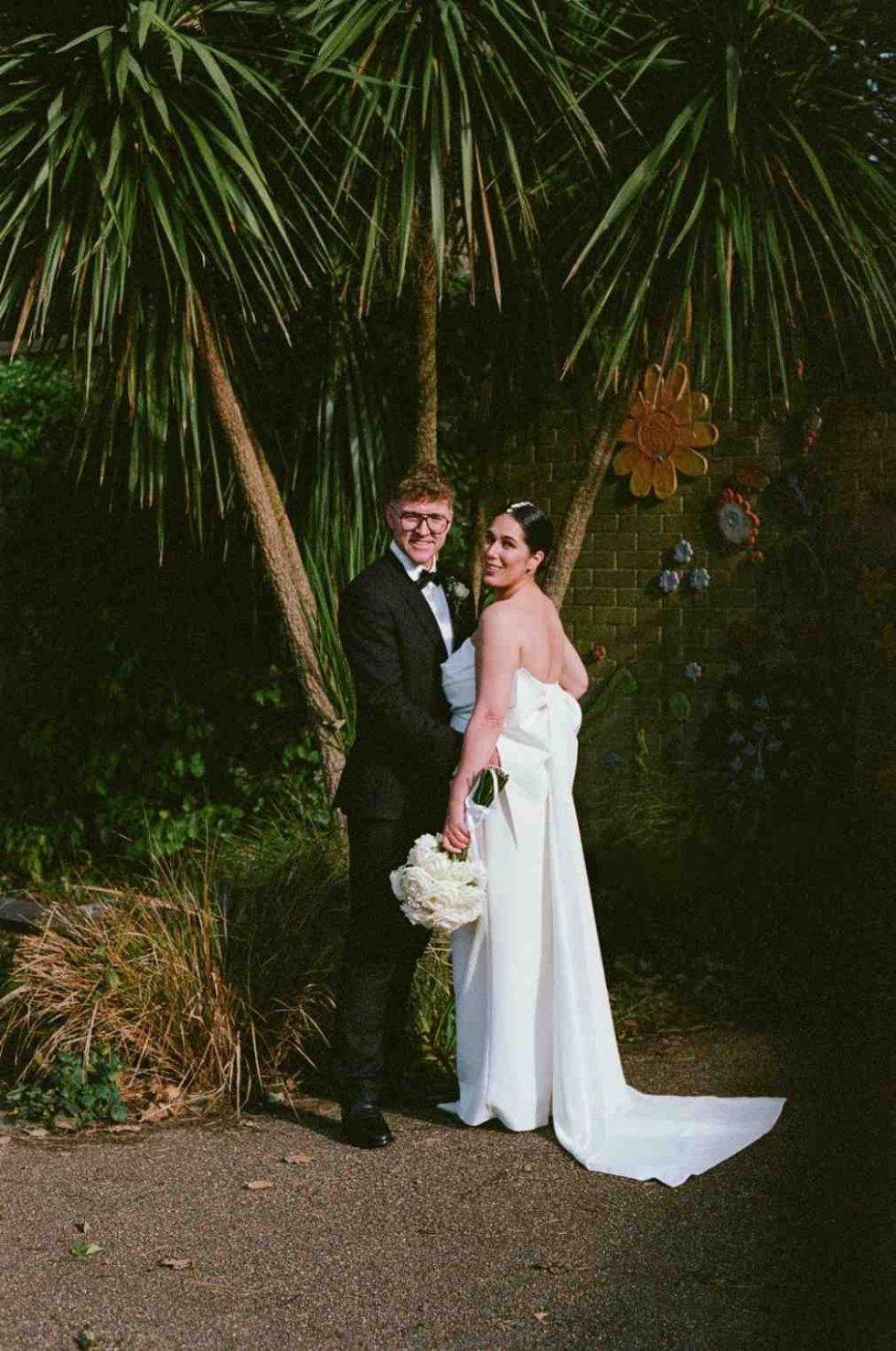 wedding couple pose under palms captured on 35mm film
