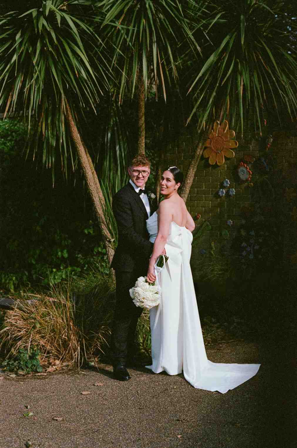 wedding couple pose under palms captured on 35mm film